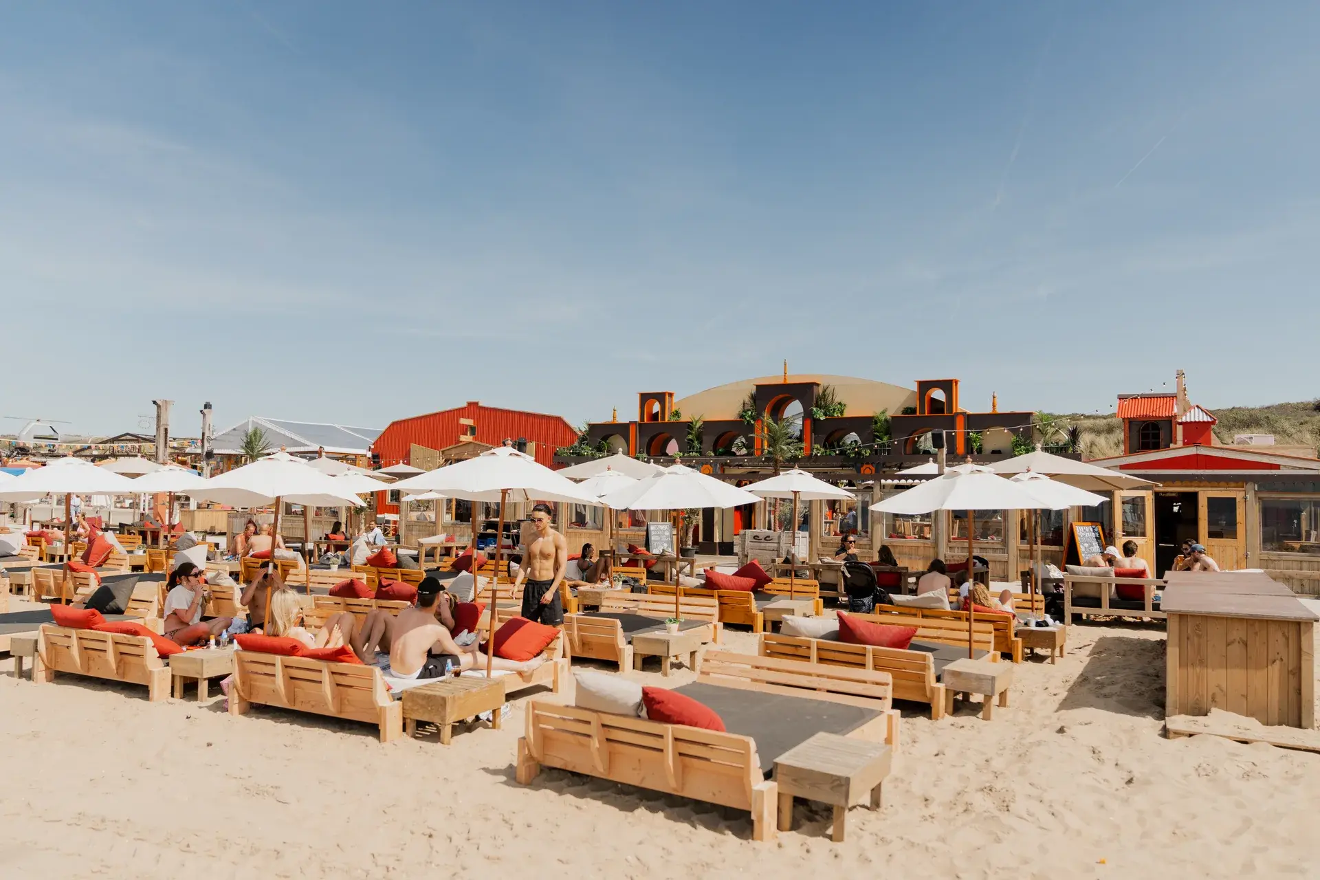 Colorado Charlie’s beach terrace with parasols and guests beside the dunes